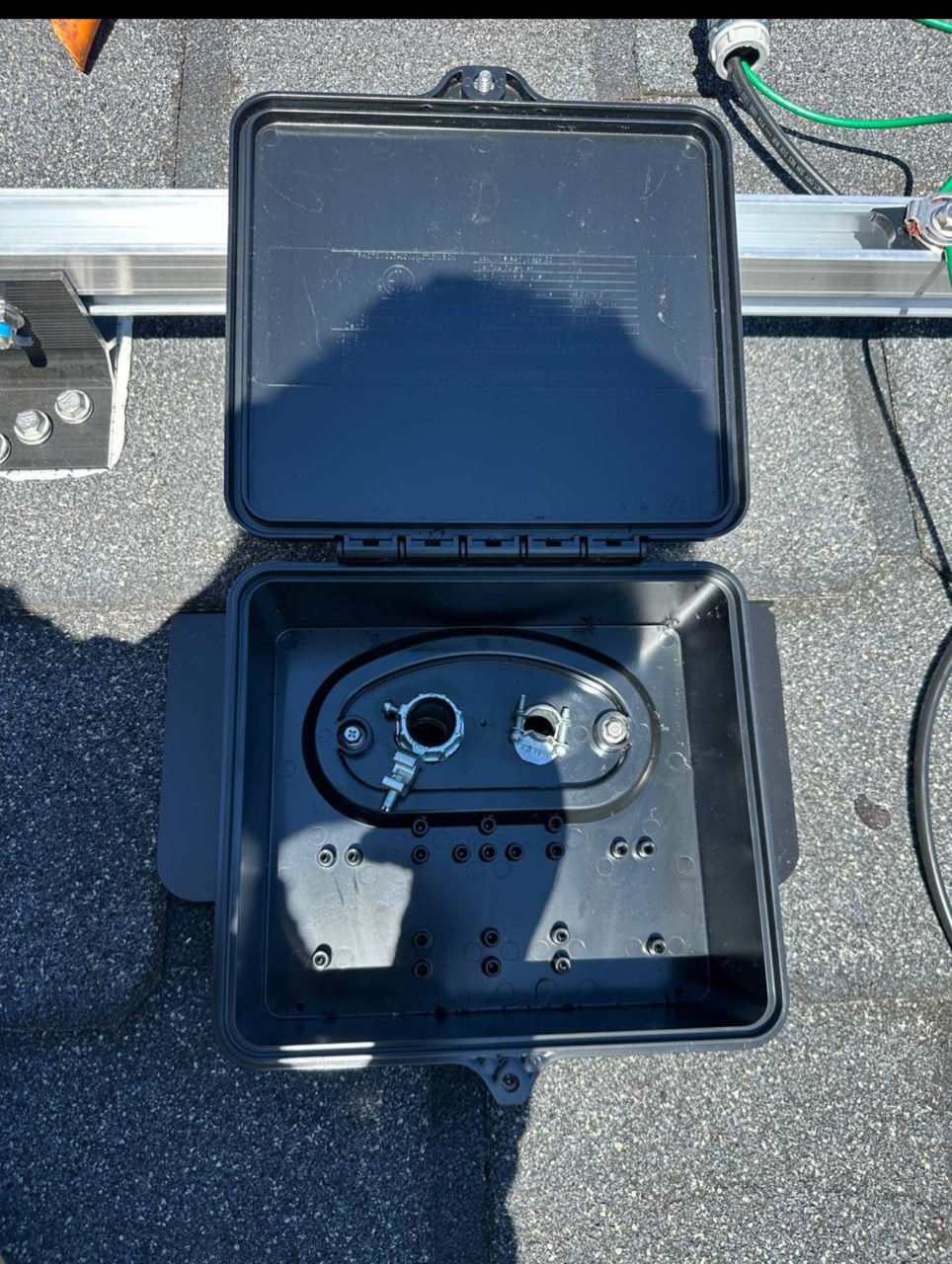 Empty weatherproof junction box open on rooftop before wiring.
